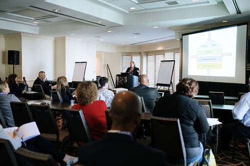 Female presenter speaking to a room full of conference attendees