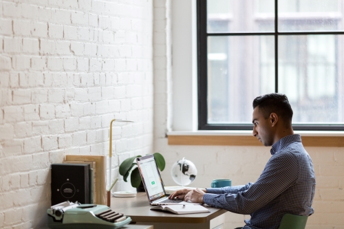 Man reviewing information from his laptop while sitting at a desk 